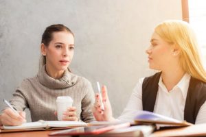 Two women talking to each others while one is taking down notes