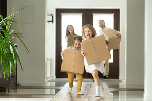 Family excited moving their new house while holding boxes