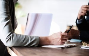 A woman's hand holding a pen while talking to a businessman about the Need a New Lease Agreement When Buying Investment Property